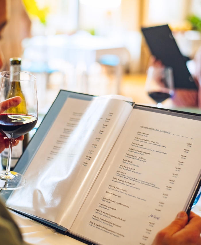Carte de restaurant imprimée consultée en salle avec verre de vin